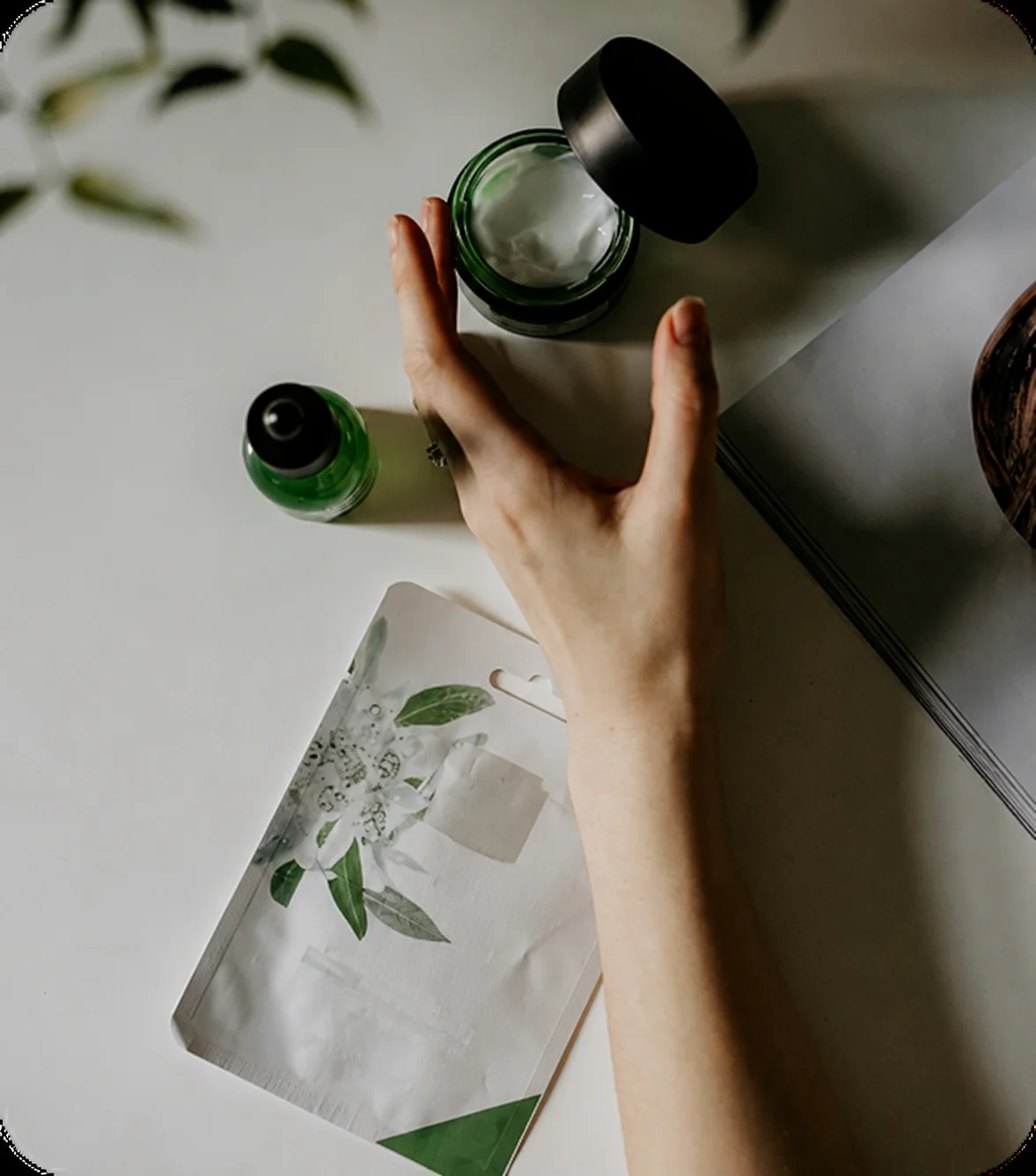 Unbranded green skincare products and a hand in soft daylight